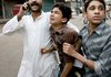  People escort an injured person to an ambulance following a bomb blast in Shiite Muslim procession in Karachi, Pakistan on Monday, Dec. 28, 2009. 