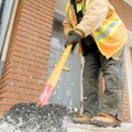Bentonville Parks Department employee Michael Van Horn scrapes ice from a sidewalk along West Centra...