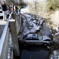 Emergency workers look over a bridge at a Mitsubishi Galant that crashed Monday in a creek along Sou...