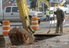 Florentino Rivera stands by to clear away dirt during sewer line work Tuesday at Eighth and Poplar streets in Rogers. Sewer lines in the intersection area, some 50 years old, are being replaced. The work at Eighth and Poplar is the first step in a long project to replace aging concrete sewer lines in Rogers.