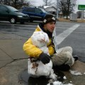 Snow buddy Marshall Bassham of Rogers sits with a snowman he made on the corner of Dixieland Road an...