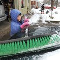 Savannah Glass, 7, sweeps the snow off a truck Sunday while her brother, Alex Glass, 9, shovels snow...