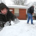 Roger Dale Moore, 4, packs a pile of snow Sunday as his father, Roger Moore, uses a shovel to gather...