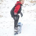 Jack Lisle, 10, of Springdale laughs as he rides a snowboard down a hill Sunday in the Har-Ber Meado...