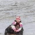 Paul Minor sleds down a hill Monday at the University of Arkansas campus in Fayetteville with his da...