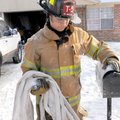 Firefighter Nathan Meeks packs hoses Monday after helping extinguish a garage fire at 1903 S. 18th S...