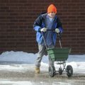 Josh Willard spreads ice melt on a sidewalk Thursday at Bentonville High School. Workers were trying...