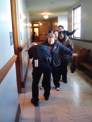 Authorities search spectators as they reenter a hearing for accused soldier-killer Abdulhakim Mujahid Muhammad. An anonymous caller suggested a weapon might be in the courtroom, delaying the hearing and prompting the extra security precautions.