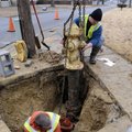 Scott McGuire with the Springdale Water Department, bottom, works Thursday on installing a fire hydr...