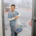 Student volunteer Hayden Graham bundles a bag of plastic water bottles Friday before placing it in a...
