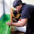 Thaddeus Thomas II with the Alpha Phi Alpha fraternity, paints a window seal Saturday at the Elizabe...