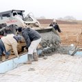A work crew deals with acres of deep mud Friday to pour concrete for a bathroom foundation at Orchar...