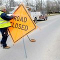 Brian Morris with the Bentonville Water Department sets a wind-swept sign back up during utilities w...