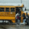 Students load buses at Springdale High School as rain moves in Thursday afternoon. The district held...