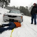 Kevin Tucker, left, of Joplin, Mo., looks for a place to hook a tow rope onto the car of Shawn Kelle...