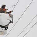 A worker with the City of Bentonville Electric Department uses a bar to knock the ice off of power l...
