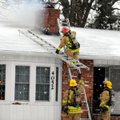 Springdale firefighters climb onto the roof of a home at 4052 Elm Springs Road to fight a flu fire F...