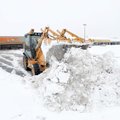 Brad Davis uses a backhoe Saturday to remove snow from the parking lot in front of Big Lots in Fayet...