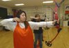  Daisy Velasquez watches an arrow fly after she released it while shooting next to Shelby Downs, right, during an archery tournament at the Crossroads School in Rogers. A three-week archery unit is part of the physical education class at the school. 
