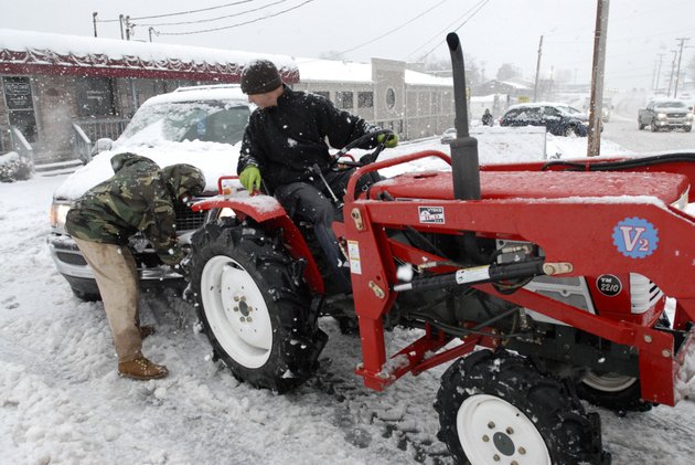 tim-carter-on-tractor-waits-as-john-carabajal-unhooks-a-chain-from-a-suv-while-helping-people-get-themselves-unstuck-from-a-parking-lot-along-highway-107-in-sherwood-on-monday