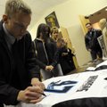 Lane Florquist signs an Arkansas War Cats jersey worn by teammate James Ahern while attending a memo...