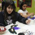 Adriana Stanley, 9, left, and Kenya Ivy, 11, both of Bentonville, decorate masks Wednesday at the Mc...