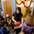 Linda Tian (center), 14, of Fayetteville hands out traditional red envelopes to children Saturday du...