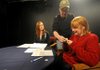 Mark Warren, center, puts a microphone on host Shannon Caine, right, and Lauren Brakebill on Friday for Fayetteville Community Access Television’s “The Caine Interviews.” In its 30-year history, Community Access Television has championed video training and local programming.