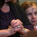 With a cross of ashes on her forehead, Grace Litzinger, 8, of Fayetteville rests against the arm of ...