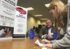 STAFF PHOTO J.S. WEDGEWORTH 
Shanda Attaway, right, writes a mock check Wednesday to Wayne Perkins of Village Insurance for coverage during a financial fitness workshop at the Rogers Public Schools annex.