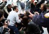 Protesters and police try to help a riot police officer after an attack by masked youths Friday in central Athens, Greece. 