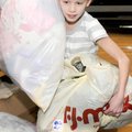 Baker Elementary School fourth-grader Sydney Visser helps carry bags of clothes, toys and children’s...