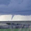 A vehicle drives across the top of Foss Lade dam with a funnel cloud in the background on March 8 in...