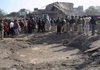  Security officials and rescue workers stand next to a crater Monday after a suicide car bomber targeted a police interrogation building in Lahore, Pakistan, killing 13 people.