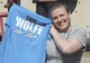 Cancer survivor Casey Wolfe poses with one of her “Casey’s Cancer Posse” team shirts on March 5 at Frisco Park in Rogers. A benefit dinner to help Wolfe pay off medical bills will be held Friday at Kirksey Middle School in Rogers.