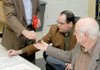 Benton County election commissioners Bill Williams, from left, Tim Hutchinson and E.J. Miller draw numbered dice Friday to determine the ballot order for 22 candidates at the Election Commission in Bentonville. The drawing was for contested races in the May 18 primary elections.