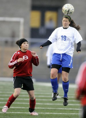Rogers High’s Natalie Breach heads the ball over Springdale High’s Shirley Izaguirre during the first half of their game Friday in Mountie Stadium in Rogers.