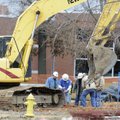 Construction workers and representatives with Arkansas Western Gas dig a hole Friday to shut off a n...