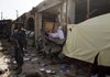 An Afghan policeman stands near shops damaged in an explosion outside the police headquarters in Kandahar, south of Kabul, Afghanistan, Sunday.