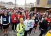 PATRIOTIC PAUSE - Jennifer LaPerre, of Bentonville, bottom center, listen as the national anthem is sung Saturday before the start of the Bentonville Half Marathon on the Bentonville Square.