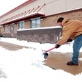 Rogers Parks and Recreation Department employee Kyle Dixon clears snow Sunday from the entrances to ...