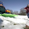  
April Oldham watches as her 20-month-old son, John Oldham, sleds down the hill Monday in front of...