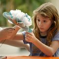  
Kayla Phillips, 9, shapes her tissue flower project while her mother, Kathy Robinson, both of Spr...