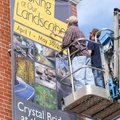Todd Grubbs, left, and Justin Lantz of Amp Sign & Banner smooth out the last wrinkles Tuesday in a b...