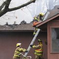 Firefighters climb to the roof at 15562 Lakecrest Drive to ventilate the smoke from a fire at the ho...
