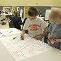 Sam Galen, 8, right, watches as his friend Jackson Plumlee, 9, signs a card for Sam during an Americ...