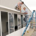 Cory Silva, left, and Heath Stamps install a 50-foot-long sunroom Monday along the south side of Hel...