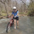 Karen Mowry of Nob Hill crosses Lee Creek barefooted during a ride Sunday at the annual Ozark Mounta...