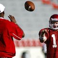 Arkansas quarterback Nick Petrino, right, tosses a ball to quarterbacks coach Garrick McGee before p...