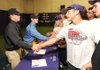 Fayetteville seniors Matt Stelte, left, and Brad Hollenbeck are congratulated by other members of the Fayetteville baseball team after signing to play college baseball during a signing ceremony Thursday at Fayetteville High. Stelte signed to play with the University of Central Arkansas in Conway while Hollenbeck signed to play with Drury University in Springfield, Mo.